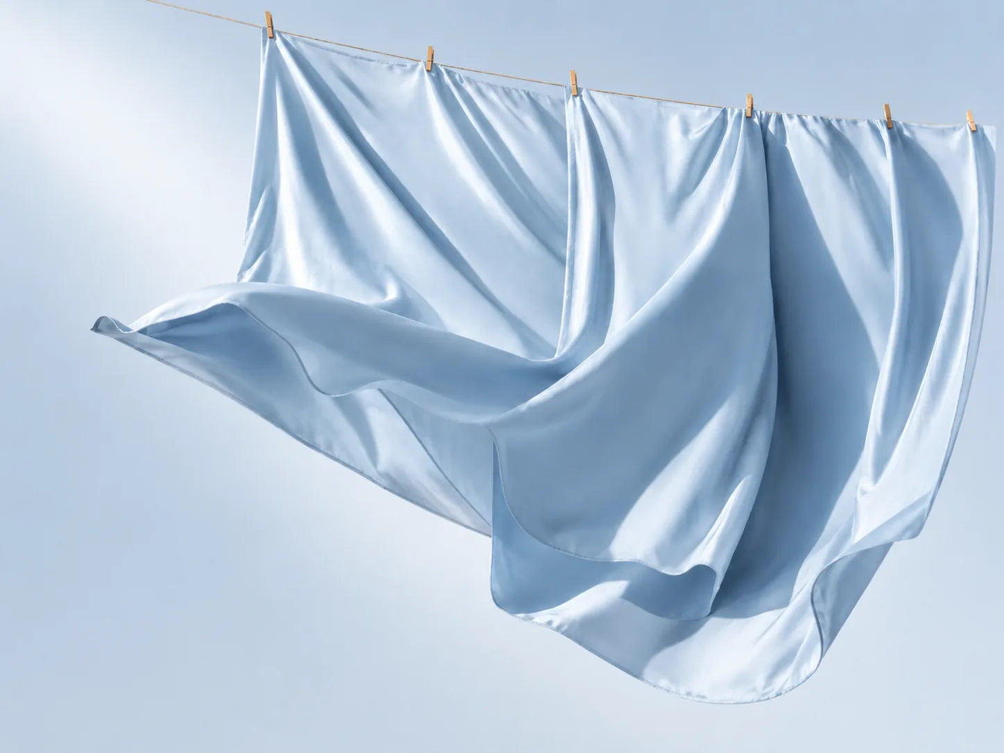 Blue cooling bedsheets hanging in soft light.